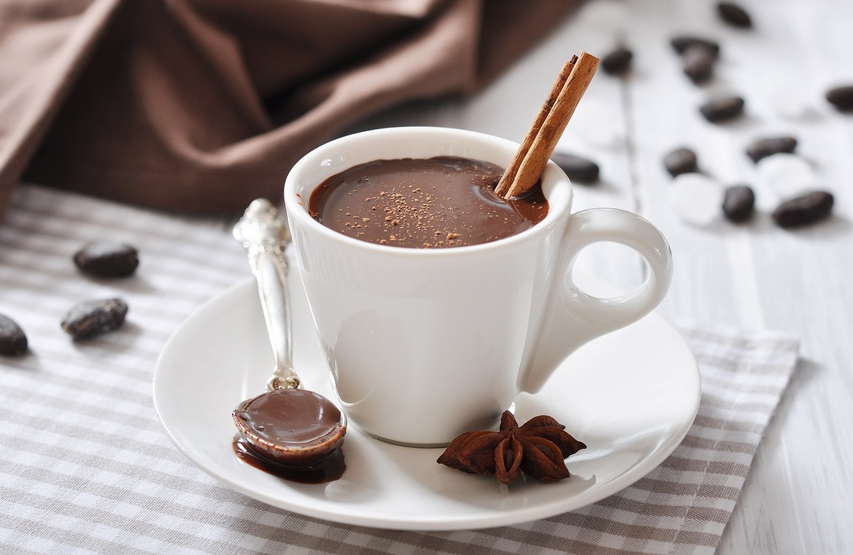Hot Chocolate in cup with cocoa powder and cinnamon stick on wooden backgro...
