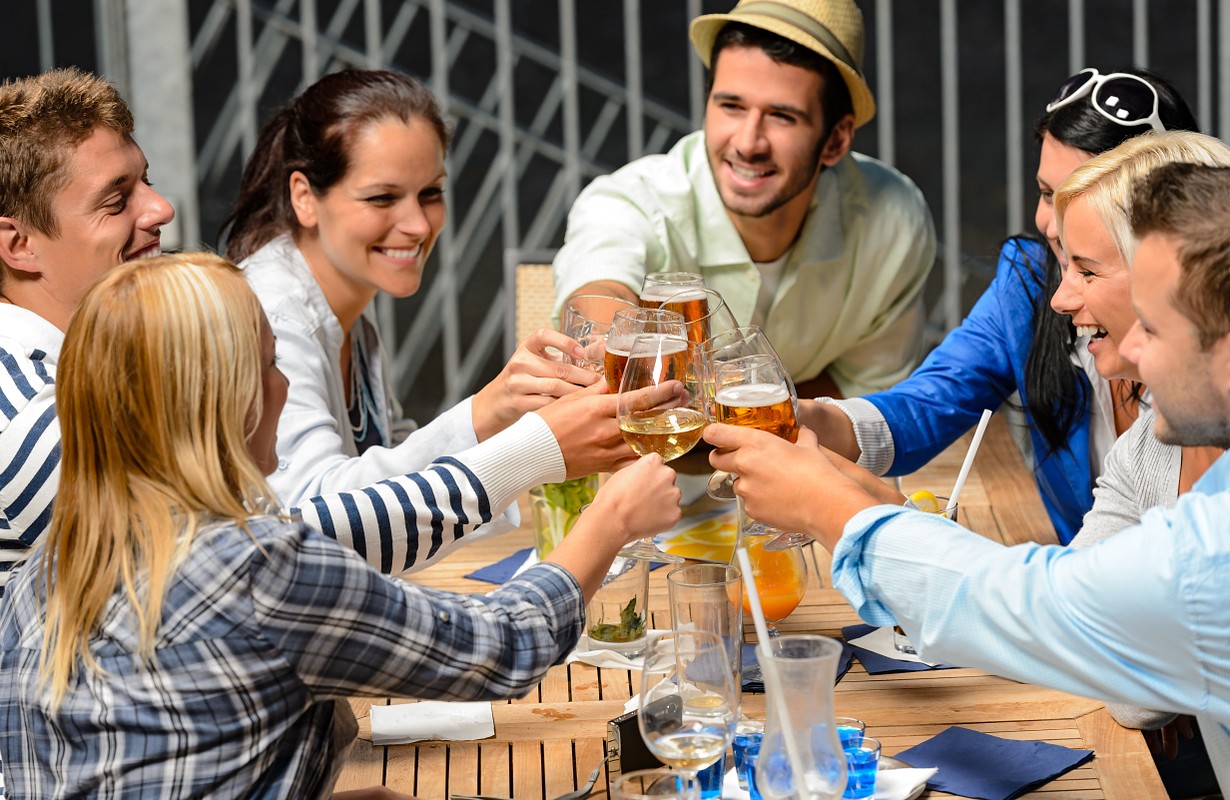 Group of friends toasting with drinks at an open-air bar in Houston, Texas 
