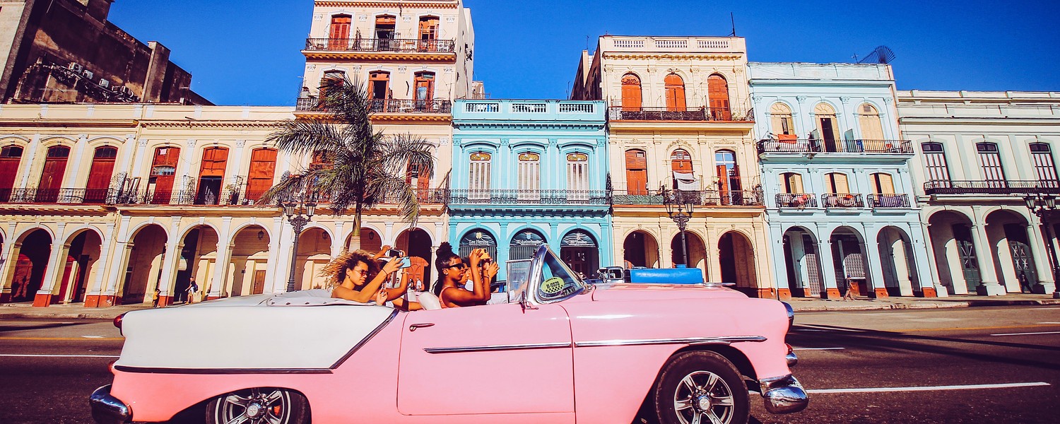 four young women in a pink old car in Havana