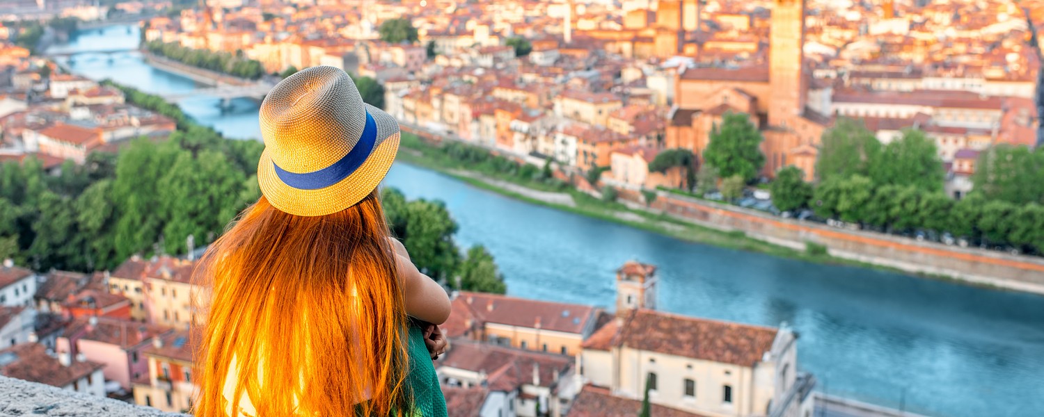Woman enjoying beautiful view on Verona city in Italy on the sunrise. Verona is famous city of love in the north of Italy.